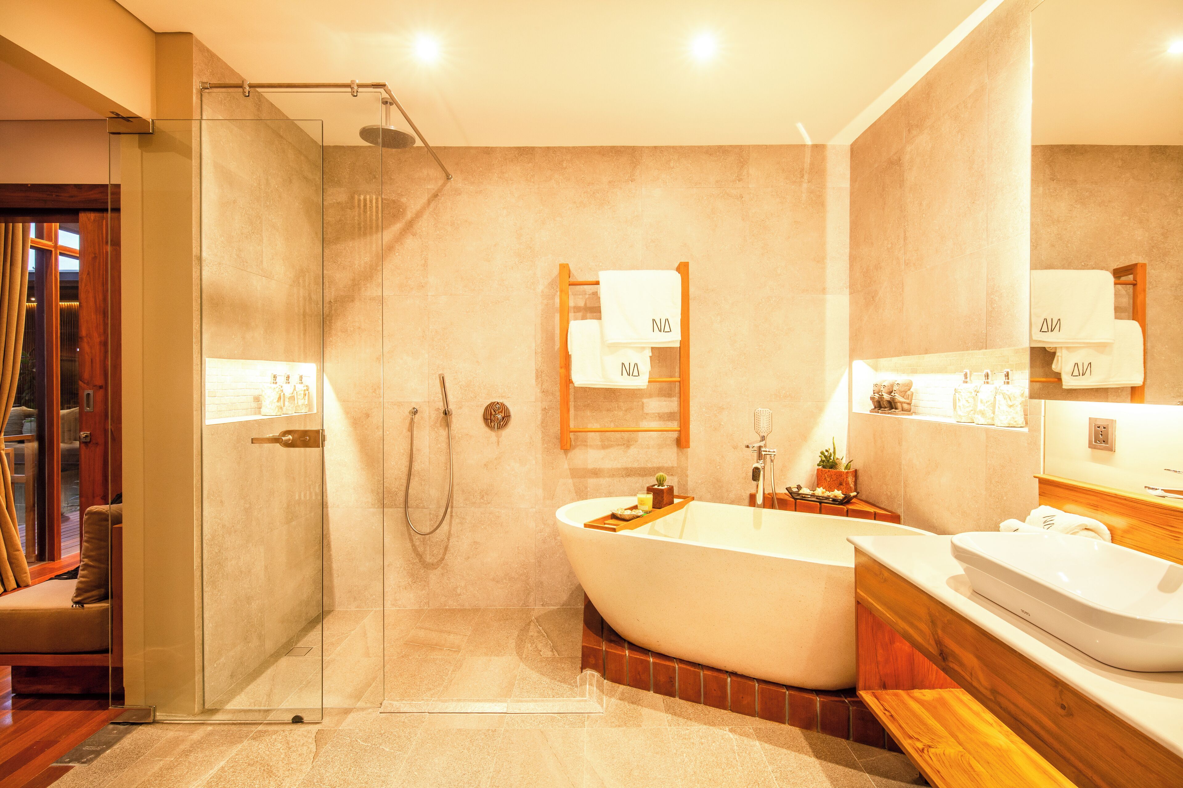 Un bagno moderno con cabina doccia in vetro, una vasca freestanding e un mobile lavabo con specchio.
