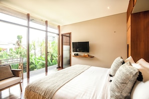 A bedroom with a large bed, a TV mounted on the wall, and a balcony with a view of greenery. - Luxury 6BR Villa, 400m to Canggu's Finns Beach (Canggu)