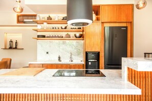 A modern kitchen with wooden cabinets, a black refrigerator, and a built-in stove. - Luxury 6BR Canggu 400m to Finns Beach (Canggu)