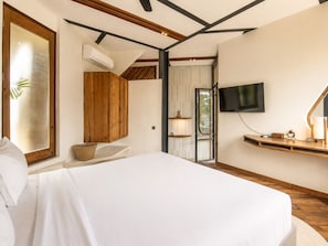 A bedroom with a bed, wooden cabinets, a TV, and a window.