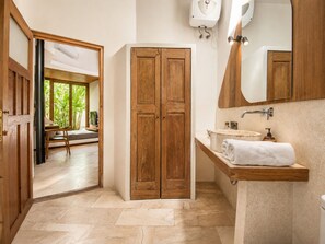 A bathroom with a wooden wardrobe, a sink with a towel, and a mirror.