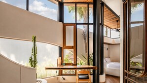 A modern interior with a curved wall, a wooden desk, a chair, and a bed. - Modern 1-br Loft With Art Deco Style and Shared Po (Canggu)