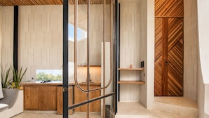 A modern kitchen with a wooden countertop, a sink, and a window overlooking greenery. - Modern 1-br Loft With Art Deco Style and Shared Po (Canggu)