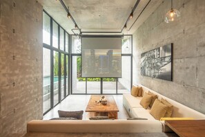 A modern living room with a large window, a wooden coffee table, a sofa, and a cityscape view.