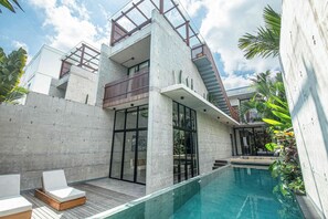 Ein modernes Haus mit Pool, Betonwänden und einer Holzterrasse.