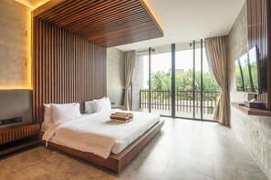 Un dormitorio moderno con una cama grande, televisor y balcón con vistas a zonas verdes.