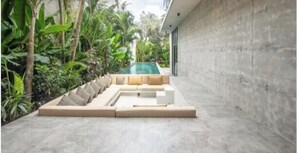 Un'area salotto esterna moderna con piscina, immersa nel verde.