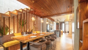 Un comedor moderno con una mesa de madera, sillas acolchadas e iluminación colgante.