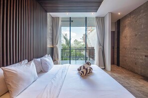 A modern hotel room with a large bed, a view of the outdoors, and a concrete wall.