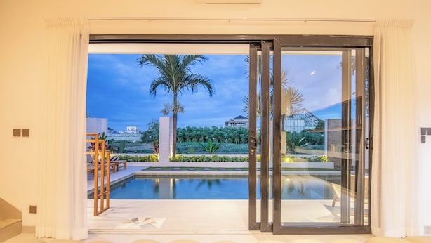 A modern living room with a large sliding glass door leading to a pool area. - 4 Bd Seminyak Rice Paddies View 4 Mins to Beach (Kerobokan)