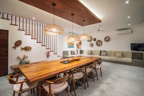Un espace repas moderne avec une table en bois, des chaises et un escalier doté de rampes en bois.