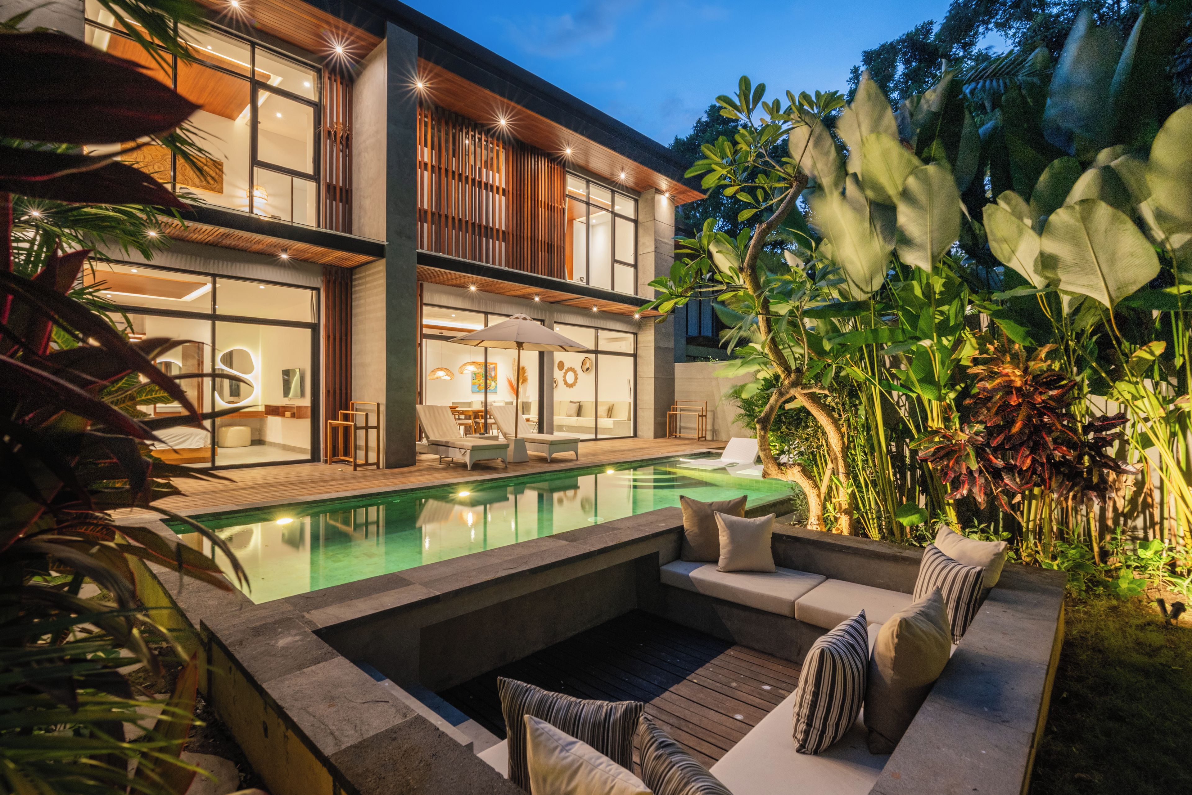 Uma casa moderna com piscina, área de estar externa e vegetação exuberante.