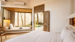 A bedroom with a large bed, a desk, a chair, and a window with curtains.