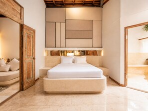Une chambre d’hôtel moderne avec un grand lit, une porte en bois et une tête de lit intégrée dotée d’un éclairage.