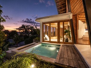 Ein modernes Haus mit Swimmingpool, einer Holzterrasse und Glastüren, die zu einem Wohnbereich führen.