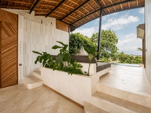A modern interior with a curved ceiling, a built-in planter with plants, and a view of the outdoors. - Stunning 2-br Penthouse With View 800m to Beach (Canggu)