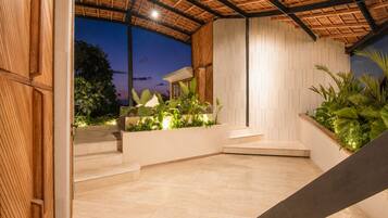 A modern outdoor area with a wooden ceiling, a white wall with a geometric pattern, and a staircase leading to a higher level.