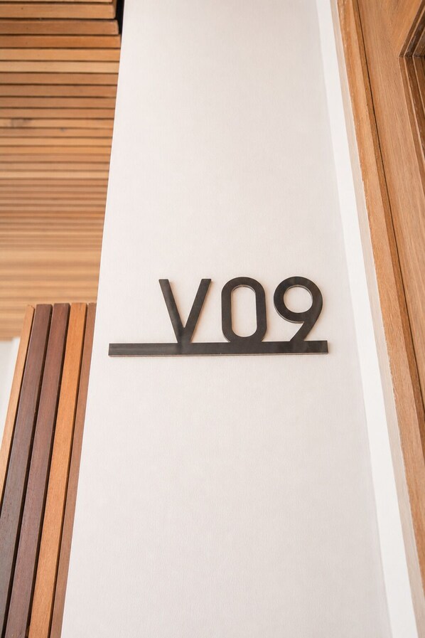 Une enseigne fixée au mur, portant les lettres « V09 », sur un mur blanc.