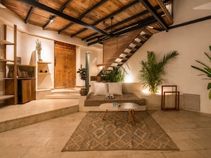 Una sala de estar acogedora con techo de madera, un sofá, una mesa de centro y una planta grande.