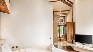 A modern hotel room with a large bed, a flat-screen TV, and a wooden ceiling. - Exquisite 1-br Loft Art Deco Charm Shared Pool (Canggu)