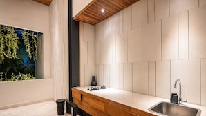 A modern kitchen with a wooden countertop, a stainless steel sink, and a view of greenery through a window. - Exquisite 1-br Loft Art Deco Charm Shared Pool (Canggu)