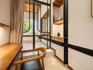 A modern kitchen with a wooden table, a chair, and a view of greenery outside. - Exquisite 1-br Loft Art Deco Charm Shared Pool (Canggu)