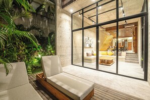 A modern interior with a glass wall, a wooden staircase, and a cozy seating area with cushions. - Modern 4BR Canggu Retreat Just 8mins to the Beach (Kerobokan)