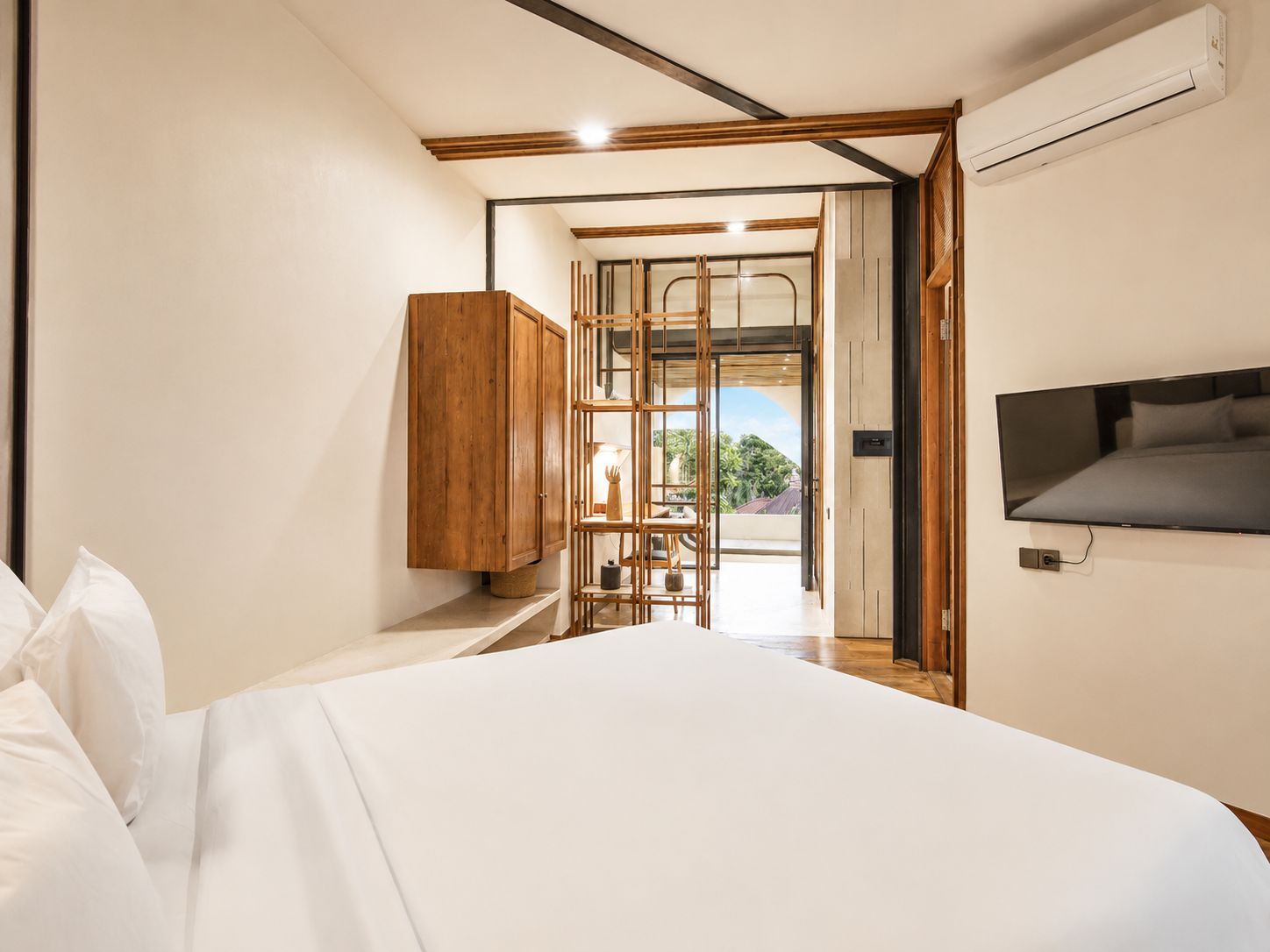 A bedroom with a bed, a wardrobe, a TV, and a view through a glass door.