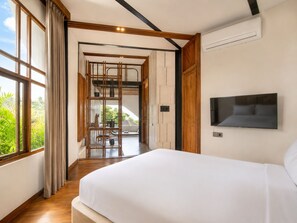 Een slaapkamer met een groot bed, een aan de muur bevestigde televisie en uitzicht op groen.