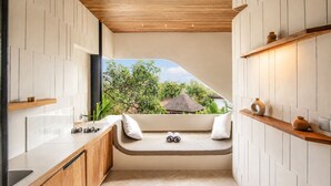 Een moderne keuken met een inbouwbank, houten planken en uitzicht op een tropisch landschap.