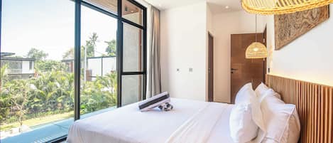 Un dormitorio moderno con una cama grande, vista a zonas verdes y una lámpara de fibra natural.