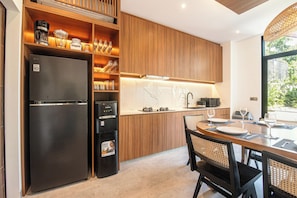 A modern kitchen with wooden cabinetry, a black refrigerator, and a dining area with a table and chairs.