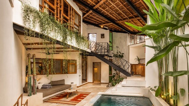 An indoor swimming pool with a staircase, wooden beams, and indoor plants. - Modern 2-br Art Deco Villa, 800m From the Beach (Canggu)