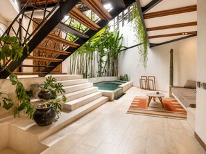 Een modern interieur met een trap, een zwembadje en kamerplanten.