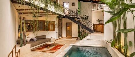 Una piscina interior con una escalera, vigas de madera y plantas de interior.