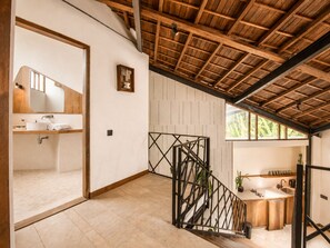 Un interno moderno con soffitto in legno, una scala, un bagno con lavandino e un'ampia finestra.