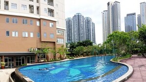 A swimming pool with a curved edge, surrounded by a brick walkway.