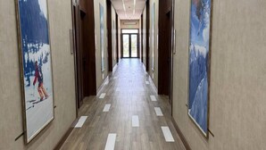 Un lungo corridoio ben illuminato, con pavimento in legno e quadri appesi alle pareti.
