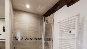 A glass-enclosed shower with a control panel, a white towel rack, and a wooden beam ceiling. - Gîte Corrézien 3 pers. Heated swimming pool (Chamboulive)
