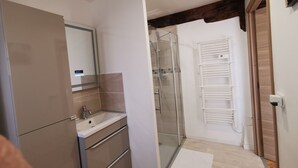A modern bathroom with a glass shower enclosure, a sink with a mirror, and a towel rack. - Gîte Corrézien 3 pers. Heated swimming pool (Chamboulive)