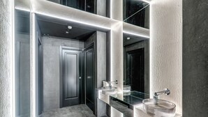 Ein modernes Badezimmer mit einem Glaswaschbecken, einem Spiegel und einer strukturierten Wand.