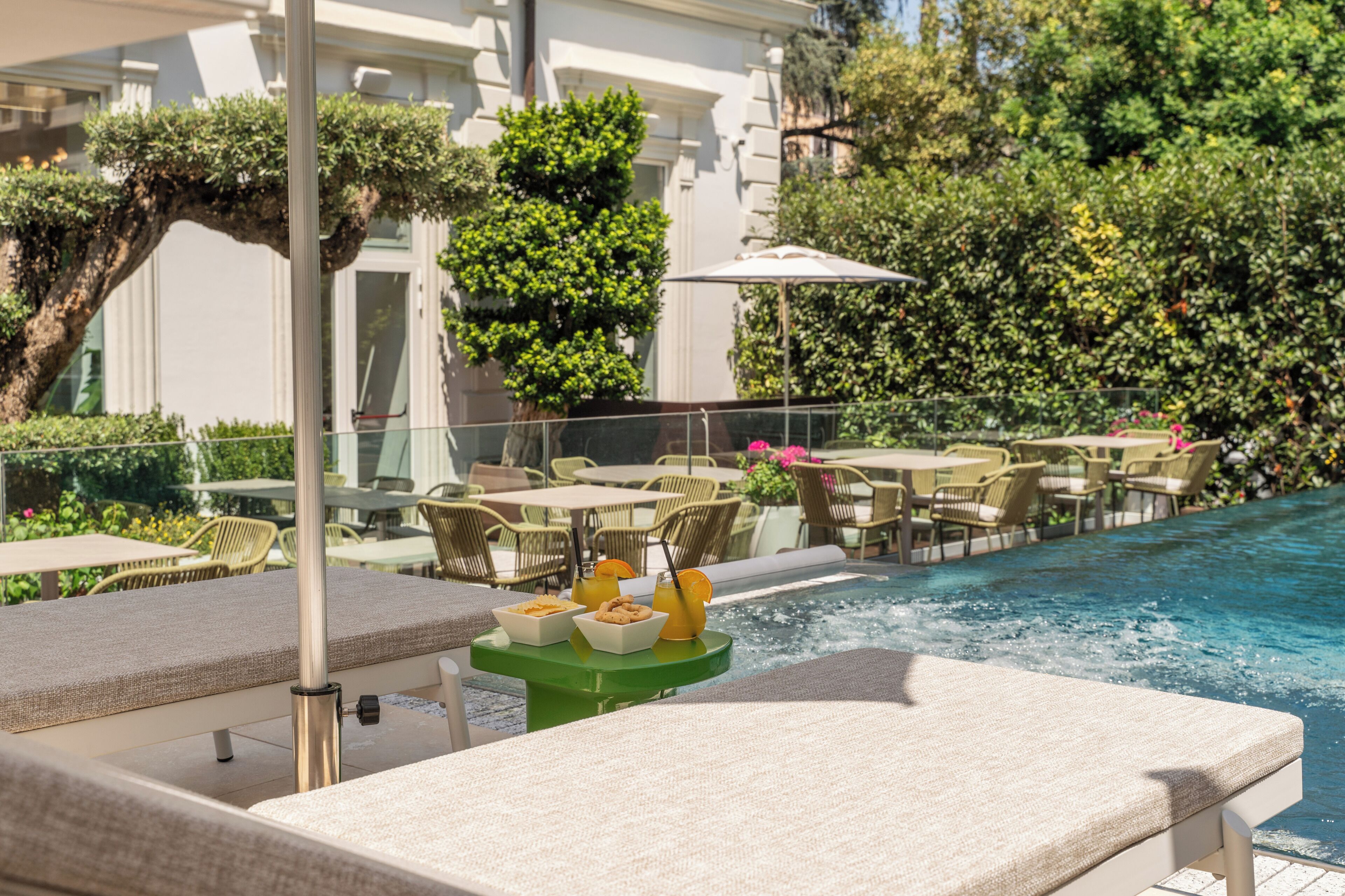 Zona junto a la piscina con sillones de descanso, una mesa con aperitivos y una bañera de hidromasaje.