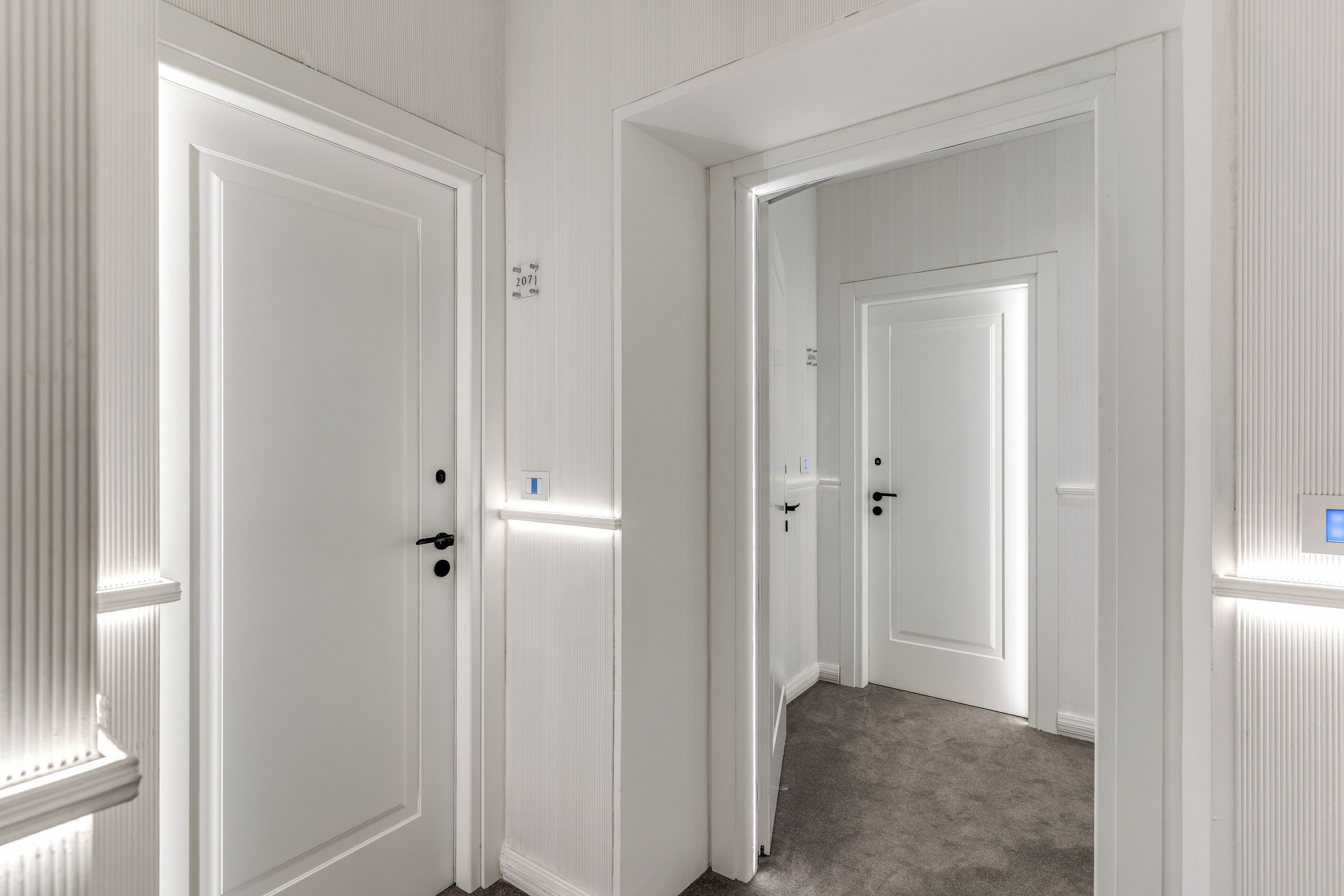 Un pasillo con puertas blancas y piso alfombrado.