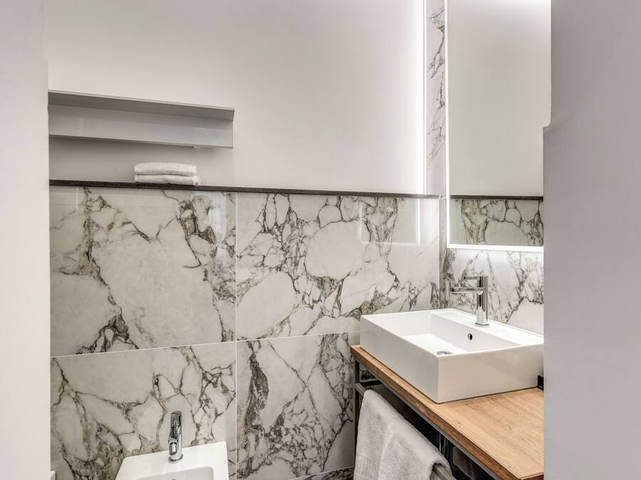 Une salle de bain moderne avec des murs en marbre, un meuble-lavabo en bois et un grand miroir.