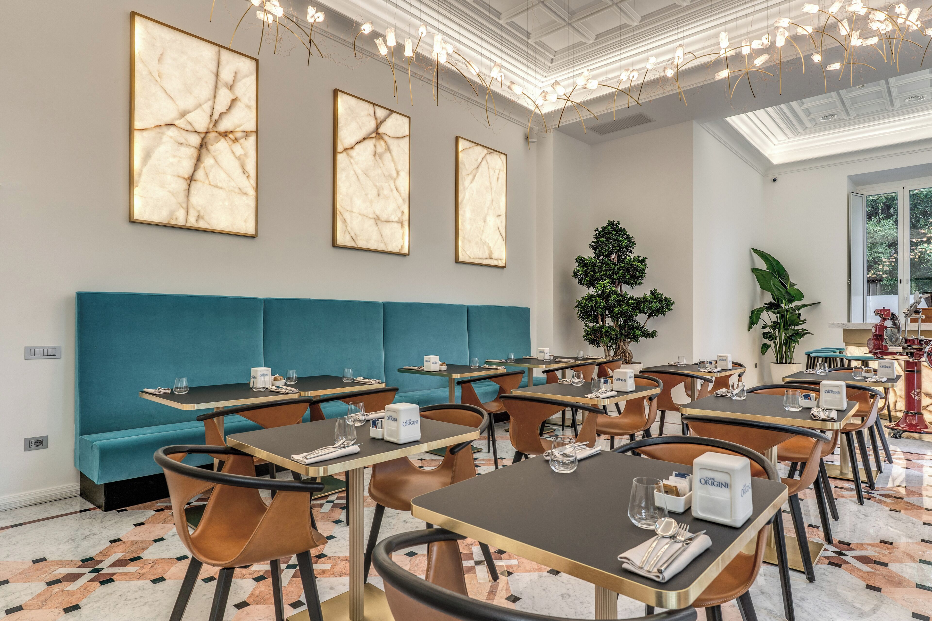 A modern restaurant interior with marble wall art, teal seating, and a variety of table settings.