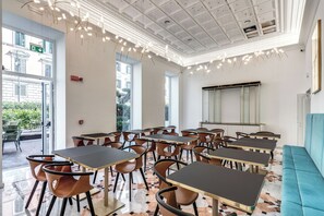A modern dining area with tables and chairs, large windows, and a ceiling with hanging lights. - The Spotlight Boutique Hotel (Rome)