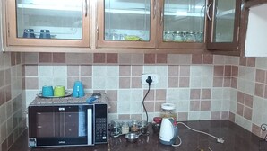 Una cocina con armarios de madera, un microondas y una tetera sobre la encimera.