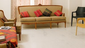 Una sala de estar con sofá, sillas, una mesita y una cortina.