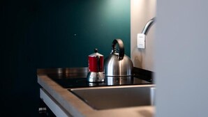 Una cocina moderna con estufa de acero inoxidable, hervidor y una olla roja.