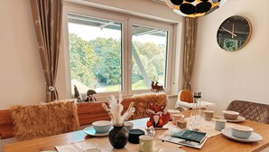 Un coin repas avec une table en bois dressée pour deux personnes, un vase contenant des herbes des pampas séchées et une décoration représentant un renard.